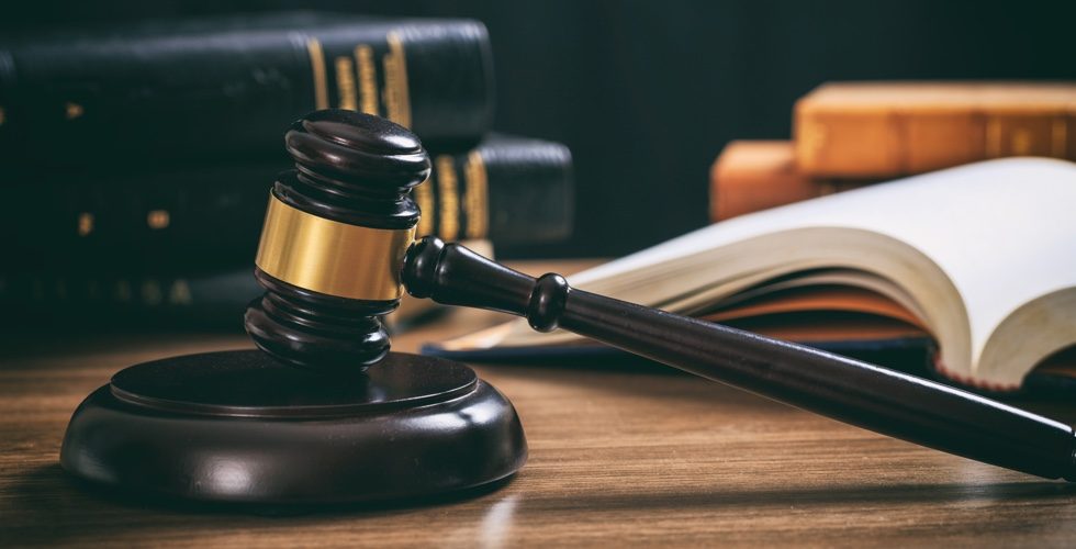 Law gavel on a wooden desk, law books background